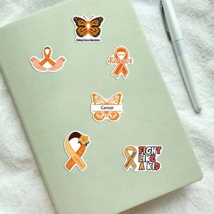 Waterproof orange leukemia awareness stickers on a notebook with ribbon and heart designs