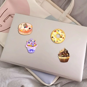 Macro view of 3D dessert stickers including macarons and donuts on a laptop lid