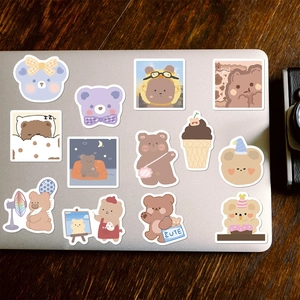 Detailed close-up of cute cartoon bear stickers applied to a silver laptop surface