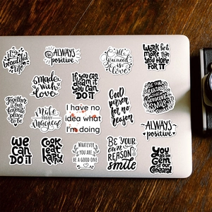 Nahaufnahme von schwarz-weißen Motivationsaufklebern auf einer silbernen Laptop-Hülle