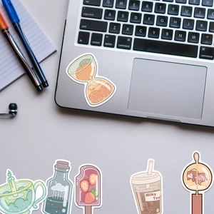 Detail showing waterproof cartoon drink bottle stickers applied to a silver laptop