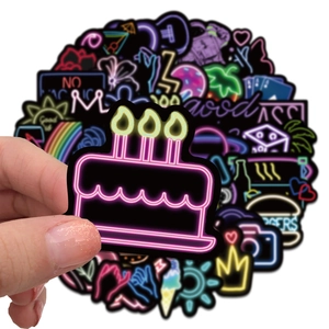 Mano che tiene un adesivo neon a torta da un set di 50 per valigie e laptop