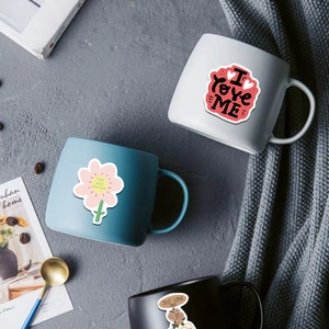 Detailed view of self love club stickers applied on ceramic coffee mugs in various colors