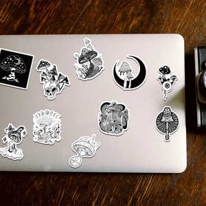 Gothic mushroom stickers with skulls and mystical eyes applied on a silver laptop surface