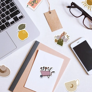 Detail showing aesthetic boho stickers on laptop and notebook in a cozy desk setup