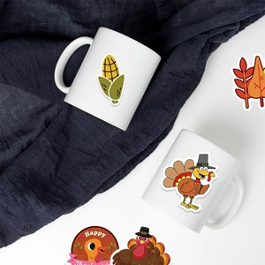 Detailed view of Thanksgiving turkey and pumpkin stickers on a white mug and fabric