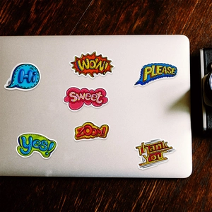 Detailed view of colorful pop art stickers on laptop including WOW and SWEET designs