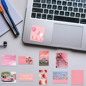 Close-up of aesthetic pink inspirational stickers on a laptop and desk setup
