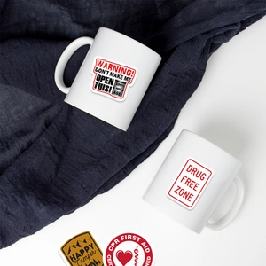 Detailed view of white ceramic mugs decorated with diverse vinyl hard hat stickers