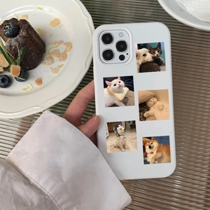 White smartphone case with cute cat and dog stickers on a stylish dessert table