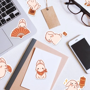 Detail of cute cartoon bunny stickers with red lanterns on laptop and phone desk setup