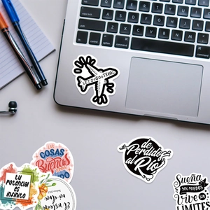 Close-up of Spanish motivational stickers on a laptop featuring travel and quote designs