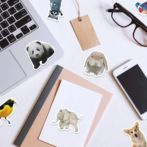 Flat lay of realistic animal stickers including panda, elephant and corgi on a laptop desk