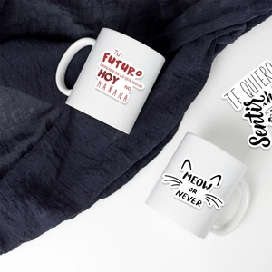 Close-up of two ceramic mugs with Spanish inspirational text and cute cat motifs