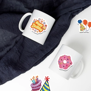 Close-up of birthday stickers with cake and donut patterns on a white ceramic mug