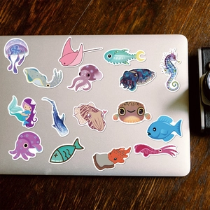 Cute cartoon marine life stickers including shark and jellyfish on a silver laptop