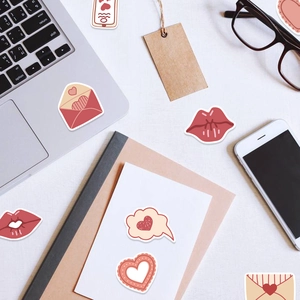 Red and pink heart-themed cartoon stickers decorating a laptop and stationery items