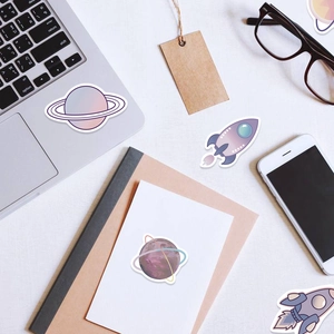 Detailed view of purple space theme stickers on a laptop and marble desk surface