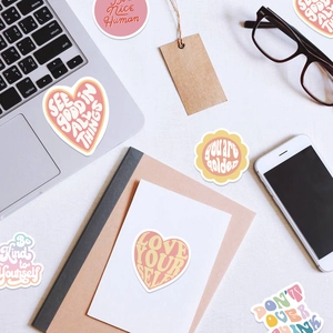 Flat lay of pink and yellow Danish pastel stickers on laptop and notebook