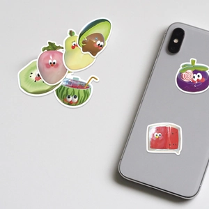 Dettaglio di adesivi di frutta 3D applicati sul retro di uno smartphone e sparsi fuori