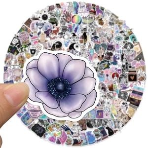 Primo piano di un adesivo floreale viola witchy tenuto in mano su una collezione