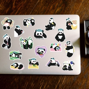 Various cute cartoon panda stickers displayed on a silver laptop and wooden table surface