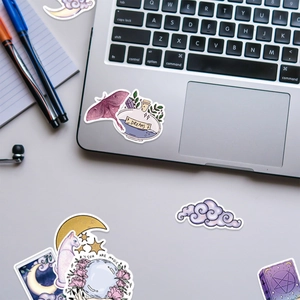 Dettaglio di adesivi magici boho con falena e pozione da sogno su un laptop grigio