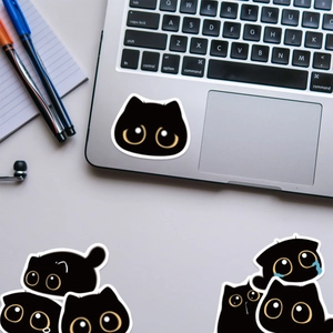 Gros plan d'autocollants mignons de chat noir dessinés à la main sur un ordinateur portable