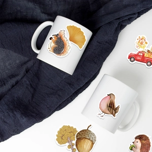 Close-up of autumn forest stickers on white ceramic mugs with squirrels and fallen leaves