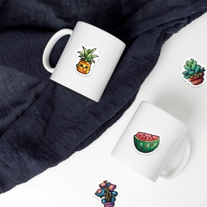 Detail of pixel art fruit stickers on white ceramic mugs with pineapple and watermelon designs
