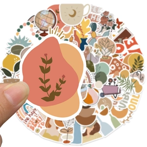 Close-up of hand holding BOHO style waterproof PVC stickers with earthy tones and floral art