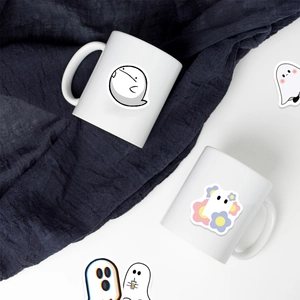 Close-up view of cute cartoon ghost stickers applied on white ceramic mugs for decoration