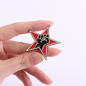 Detail of red enamel star brooch with black raised fist symbol held in hand