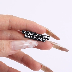 Makroaufnahme einer Emaille-Brosche mit I might be wrong but I doubt it Spruch in der Hand