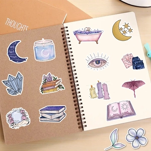 Detail of purple magical stickers on notebook featuring moon, crystals, and moths
