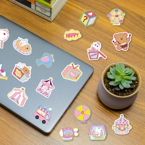 Cute cartoon stickers featuring bears and carousels applied on a laptop and wooden desk