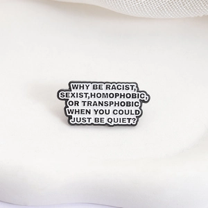 Minimalist enamel pin with black and white social justice text quote on white tray