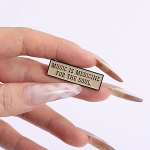 Macro detail of music is medicine for the soul enamel pin badge on fingers