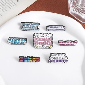 Set mit 7 bunten Emaille-Anstecknadeln für psychische Gesundheit auf weißem Keramikteller