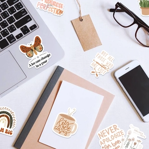 Flat-lay view showing boho stickers on laptop and phone for aesthetic decoration