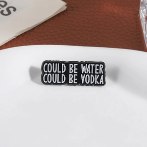 Spilla smaltata nera con frase Could Be Water Could Be Vodka su espositore bianco