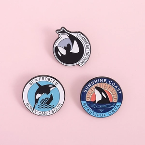 Set di tre spillette in smalto a forma di orca con tema marino su sfondo rosa
