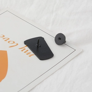 Macro view of black enamel brooch back with sharp pin and secure rubber clutch
