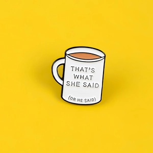 Detail of coffee cup enamel pin with That's What She Said text on yellow background