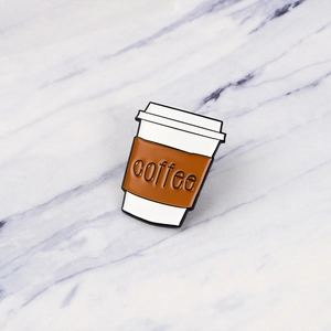 Cartoon enamel coffee cup pin badge with coffee lettering on white marble surface