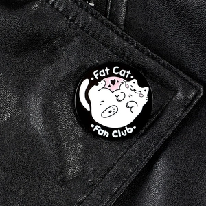 Close-up of a Fat Cat Fan Club enamel pin featuring white cartoon cats on a leather jacket