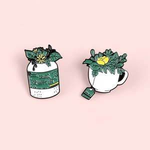 Détail de pin's émaillés avec flacon de fleurs et tasse de thé aux plantes vertes