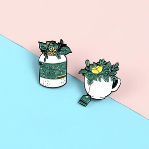 Détail de pin's en émail représentant un flacon de médicament et une tasse avec des plantes