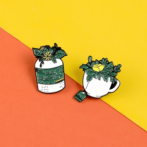 Détail de broches en émail créatives avec plantes dans un flacon et une tasse de thé