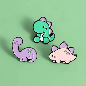 Lot de trois pin's émaillés mignons dinosaures colorés sur fond vert clair